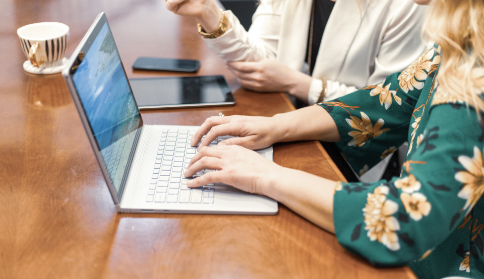 Two people working through financial papers at a table with a laptop
